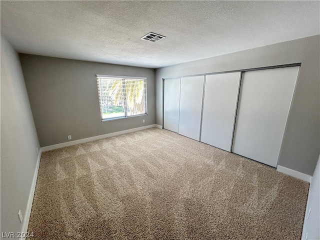 unfurnished bedroom featuring light colored carpet, a closet, and a textured ceiling