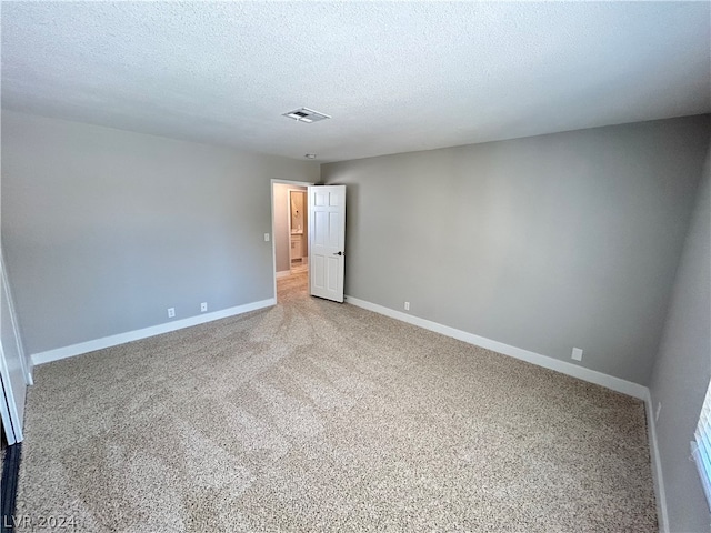 carpeted empty room with a textured ceiling