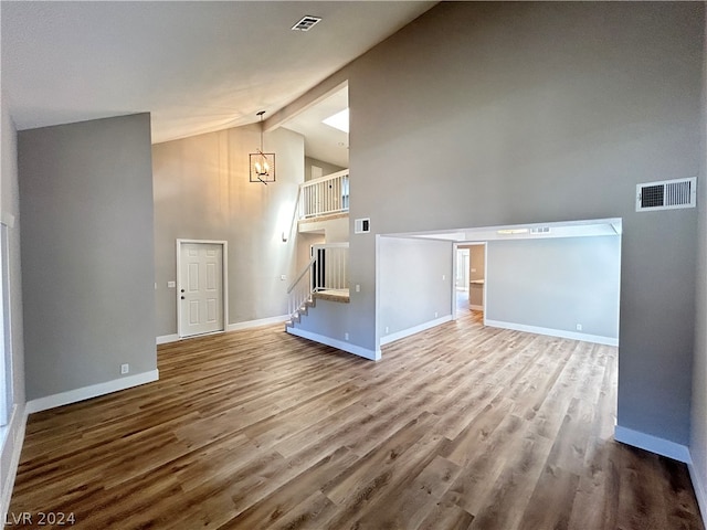 bonus room with high vaulted ceiling, a notable chandelier, and hardwood / wood-style flooring