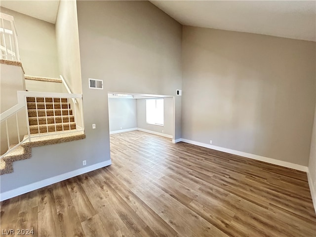 unfurnished living room with high vaulted ceiling and hardwood / wood-style floors