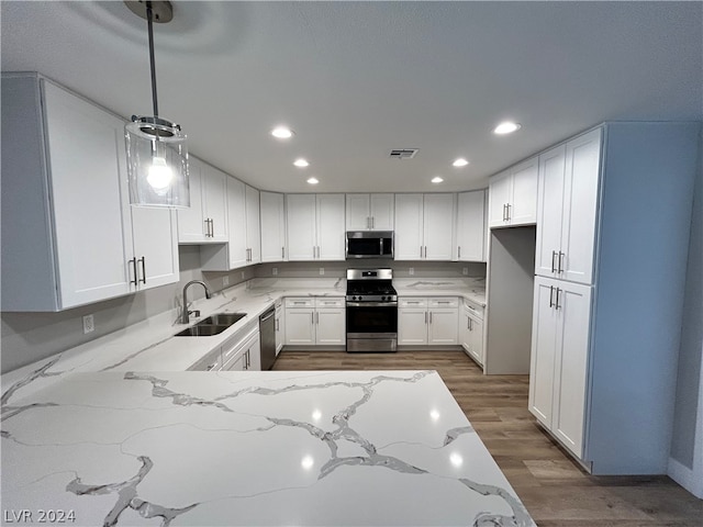 kitchen with light stone countertops, pendant lighting, stainless steel appliances, and dark wood-type flooring