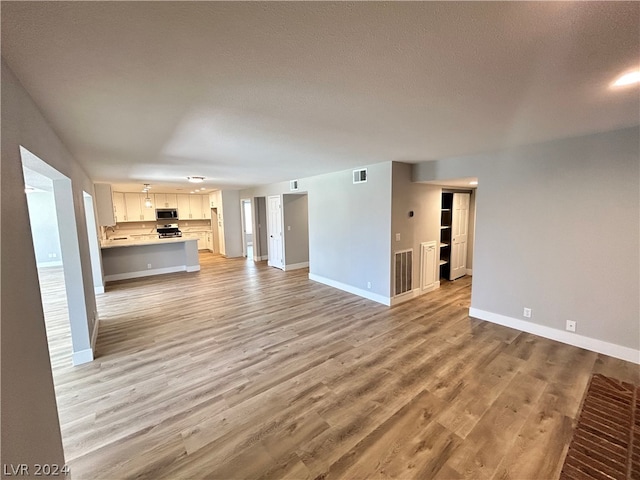 unfurnished living room featuring light hardwood / wood-style flooring and sink