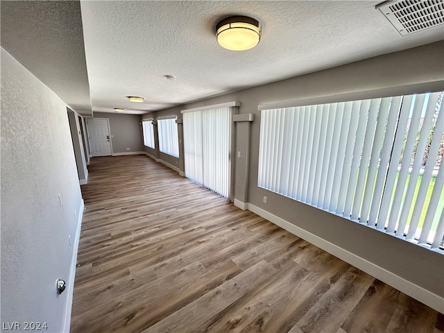 unfurnished room featuring hardwood / wood-style flooring, plenty of natural light, and a textured ceiling