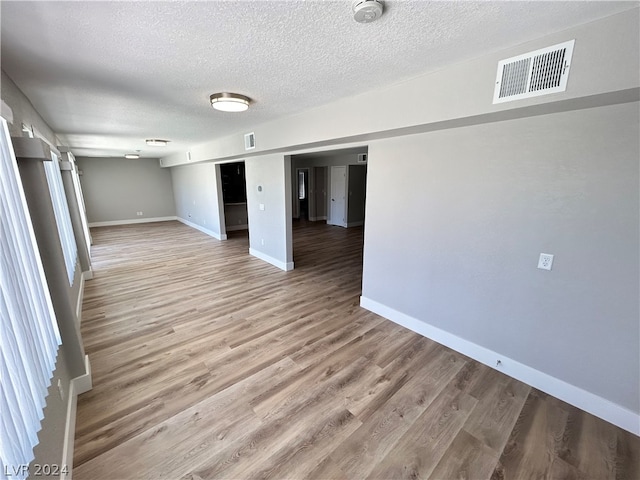 empty room with light wood-type flooring and a textured ceiling