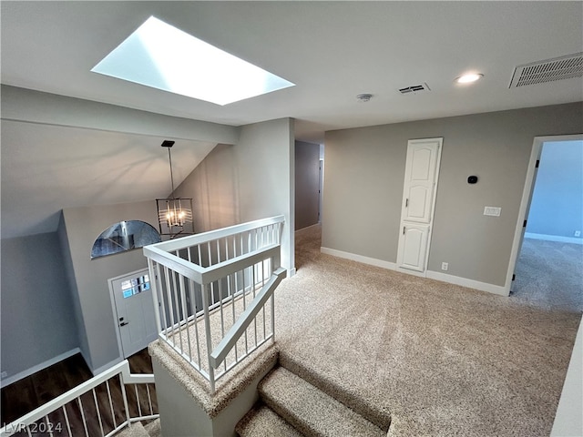 stairs featuring light colored carpet, lofted ceiling with skylight, and a chandelier