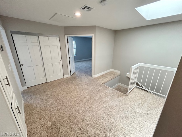 bedroom with a skylight, light colored carpet, and a closet