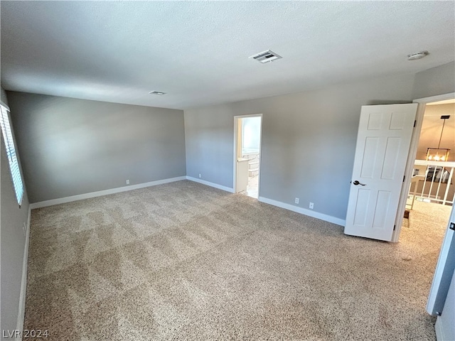 unfurnished room with a chandelier, light colored carpet, and a textured ceiling