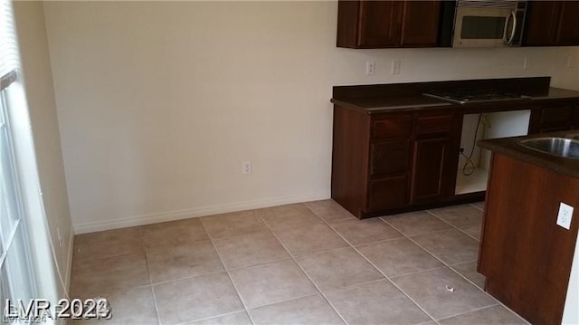 kitchen featuring dark brown cabinetry and light tile floors