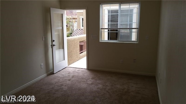 spare room featuring dark colored carpet