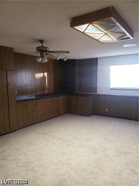 carpeted spare room featuring wooden walls and ceiling fan