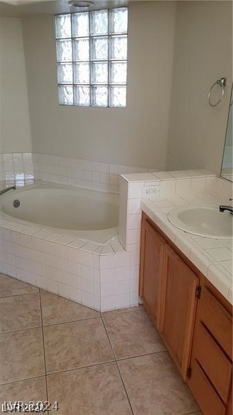 bathroom with tile flooring, tiled bath, and vanity