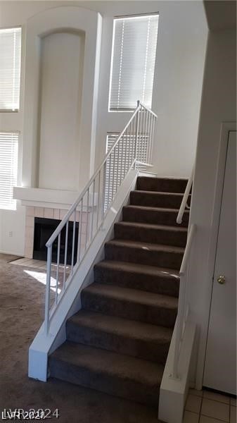 stairs featuring a tile fireplace and tile flooring