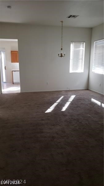 carpeted spare room with a notable chandelier