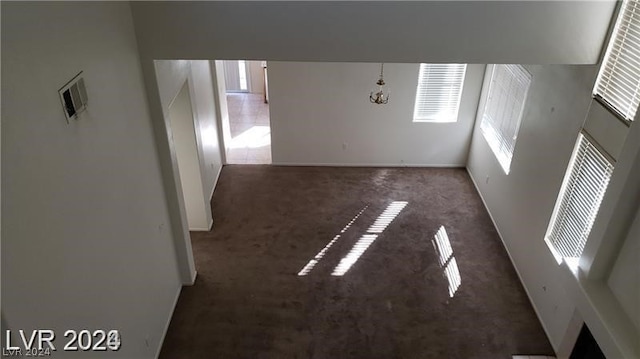 empty room with dark carpet and a chandelier