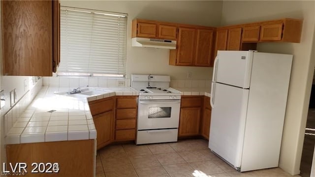 kitchen featuring light tile flooring, sink, white appliances, and tile countertops