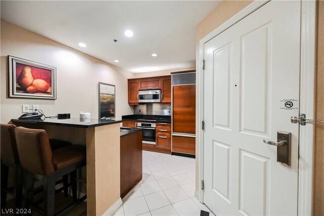 kitchen featuring appliances with stainless steel finishes, light tile flooring, and a breakfast bar area