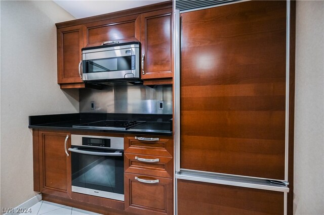 kitchen with light tile floors, dark stone counters, and stainless steel appliances