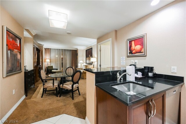 kitchen featuring dark stone counters, light colored carpet, kitchen peninsula, dishwasher, and sink