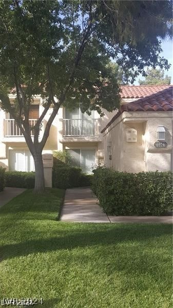 view of front of house with a balcony and a front lawn