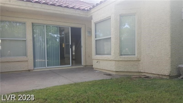 doorway to property with a patio area and a lawn