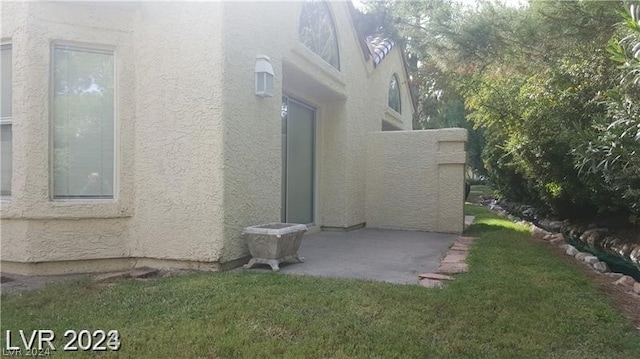 view of property exterior with a patio area and a yard