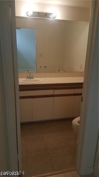 bathroom featuring toilet, tile flooring, and vanity