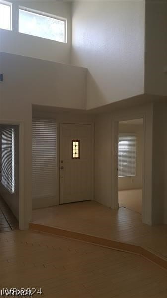 entryway with a towering ceiling and light wood-type flooring