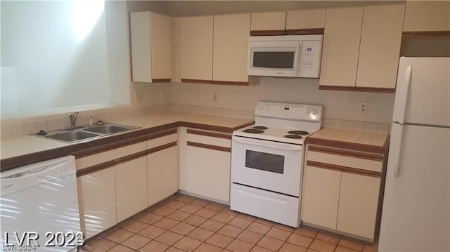 kitchen with sink, white appliances, tile countertops, and light tile floors