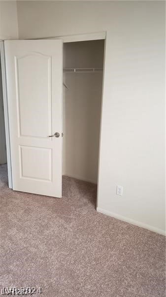 unfurnished bedroom with light colored carpet and a closet