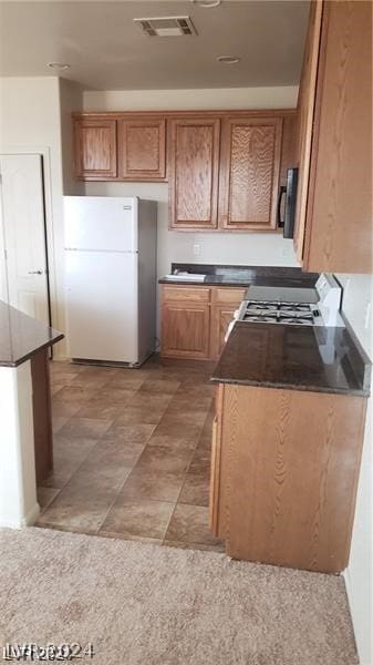 kitchen featuring light tile floors, white refrigerator, and stove