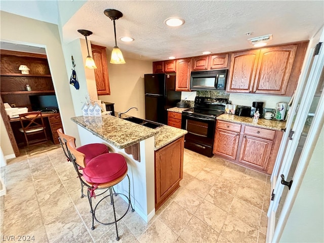 kitchen featuring a breakfast bar, black appliances, pendant lighting, sink, and light tile flooring