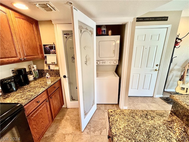 washroom featuring light tile floors and stacked washer and dryer