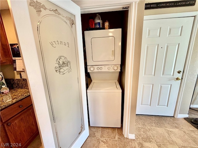 washroom with light tile flooring and stacked washer and dryer