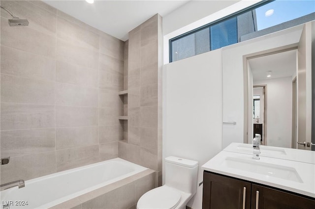 full bathroom featuring vanity, tiled shower / bath, and toilet