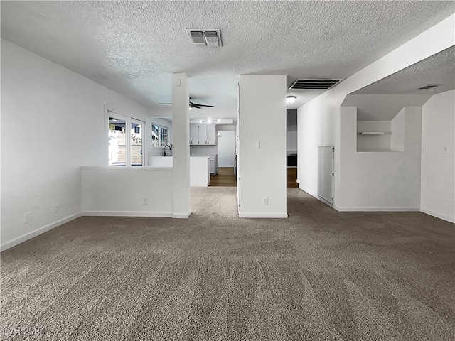 unfurnished living room with ceiling fan, carpet flooring, and a textured ceiling