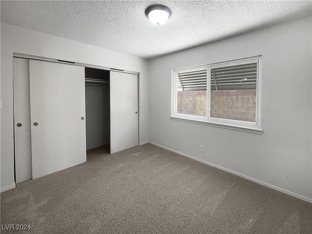 unfurnished bedroom with a textured ceiling, a closet, and carpet