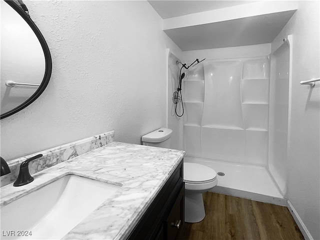 bathroom featuring hardwood / wood-style floors, a shower, toilet, and vanity