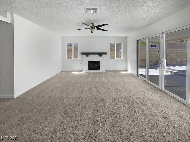 unfurnished living room featuring a wealth of natural light, carpet flooring, ceiling fan, and a brick fireplace