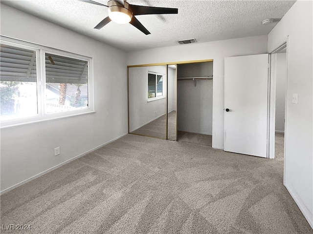 unfurnished bedroom featuring ceiling fan, a closet, multiple windows, and carpet flooring