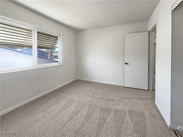 unfurnished room featuring light colored carpet and a textured ceiling