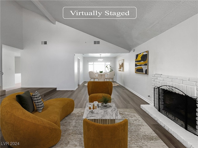 living room featuring dark hardwood / wood-style flooring, a fireplace, a textured ceiling, and vaulted ceiling with beams