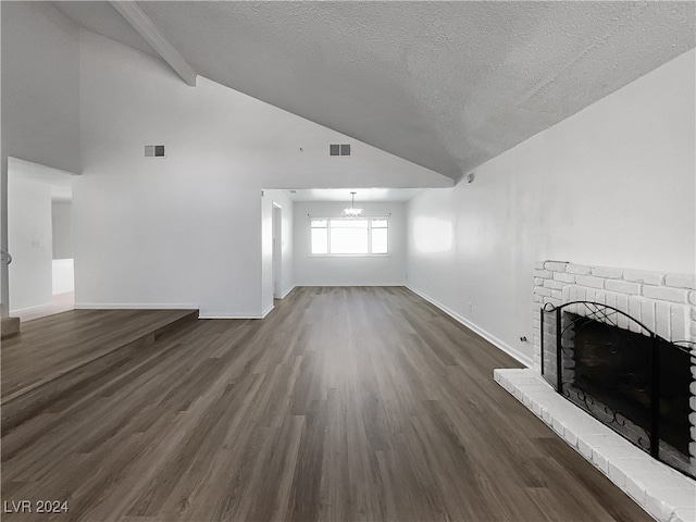 unfurnished living room with beamed ceiling, dark wood-type flooring, a textured ceiling, and a brick fireplace