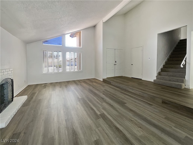 unfurnished living room featuring high vaulted ceiling, wood-type flooring, a textured ceiling, and a fireplace