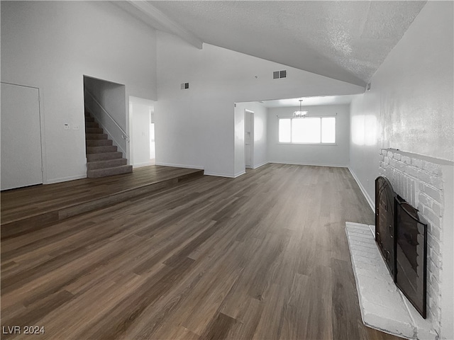 unfurnished living room featuring a fireplace, a textured ceiling, high vaulted ceiling, and hardwood / wood-style floors