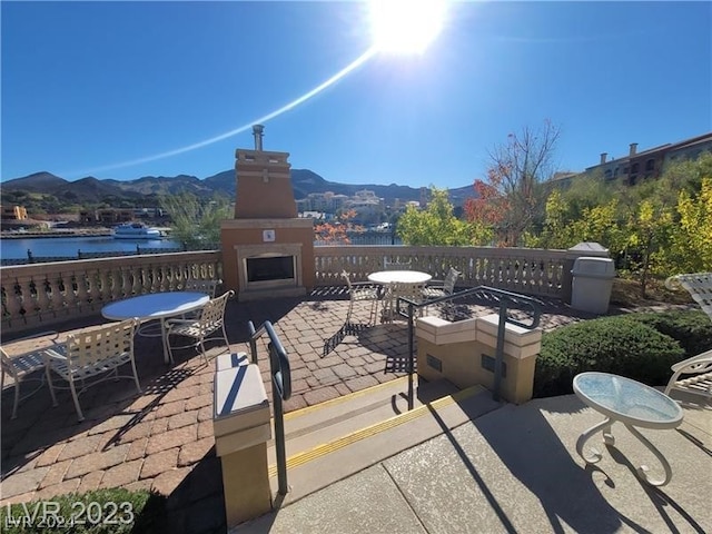 view of patio / terrace featuring a water and mountain view and exterior fireplace