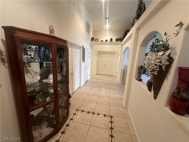 corridor featuring a towering ceiling and light tile flooring