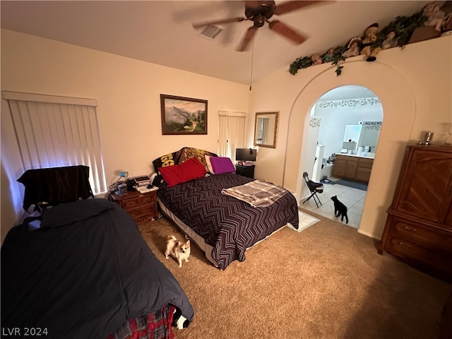 bedroom with carpet floors, ensuite bathroom, ceiling fan, and vaulted ceiling