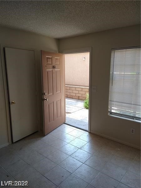 tiled empty room featuring a textured ceiling