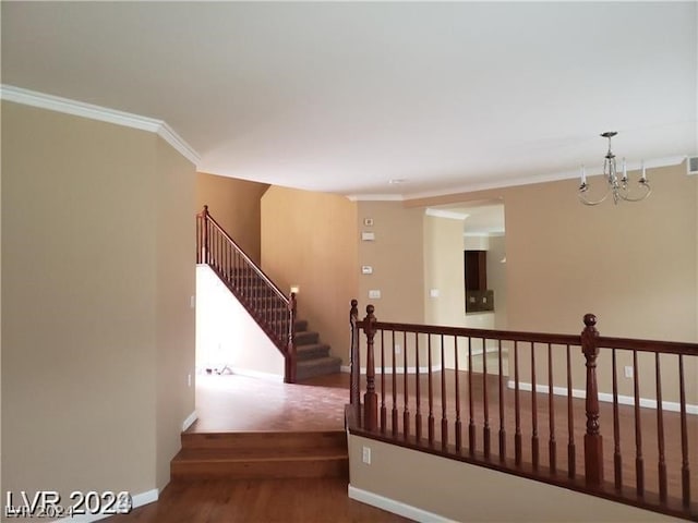 staircase with ornamental molding, a notable chandelier, and dark carpet