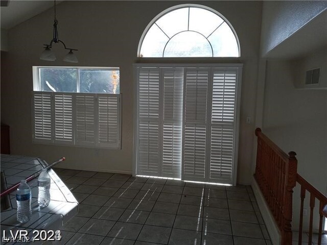 foyer with high vaulted ceiling and dark tile flooring